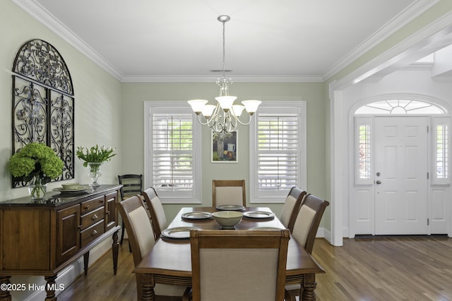 dining room with ornamental molding, baseboards, a notable chandelier, and wood finished floors