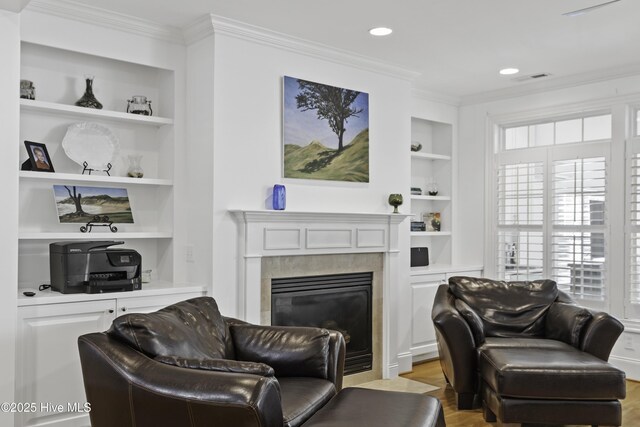 living room with light wood finished floors, built in features, and ornamental molding