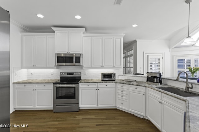 kitchen with white cabinetry, appliances with stainless steel finishes, ornamental molding, and a sink