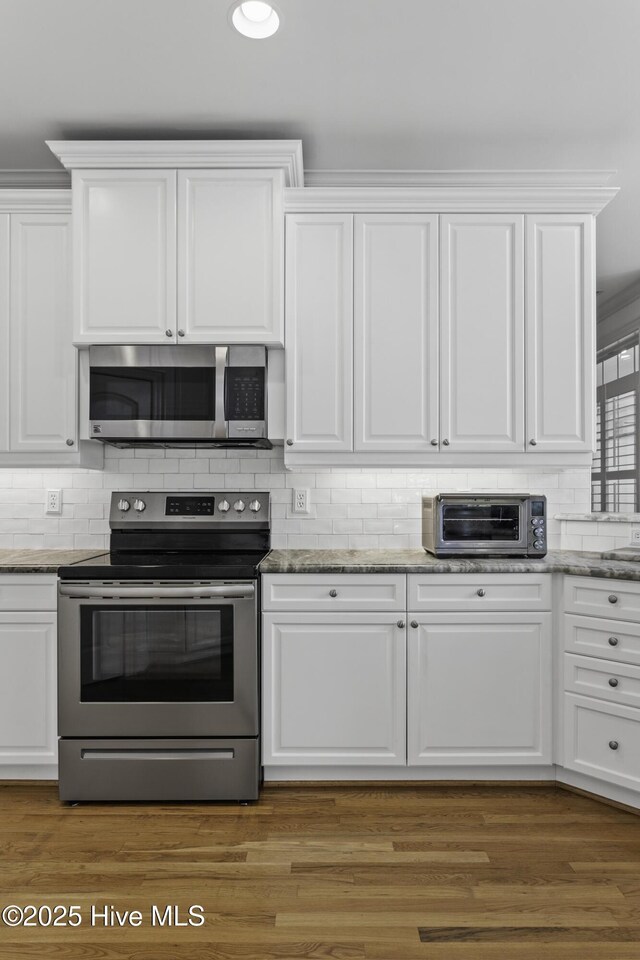 kitchen with appliances with stainless steel finishes, a toaster, and white cabinetry