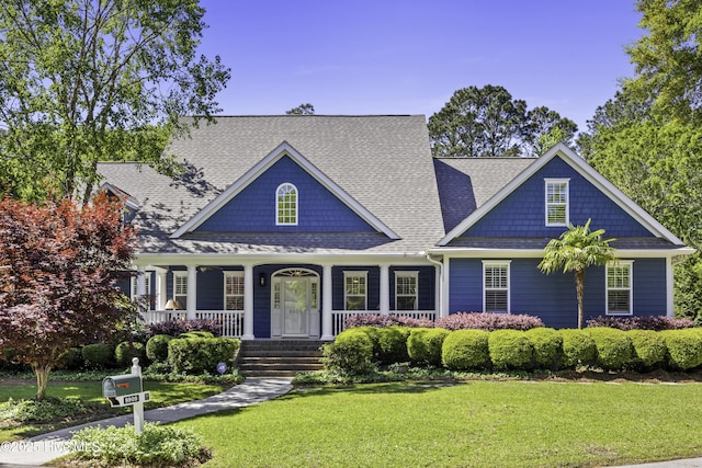 craftsman house featuring a porch, roof with shingles, and a front yard