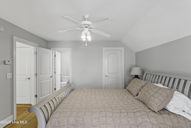 bedroom with ensuite bath, lofted ceiling, a ceiling fan, and wood finished floors