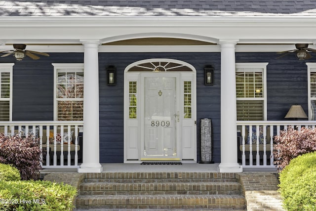 entrance to property featuring a ceiling fan, a shingled roof, and covered porch