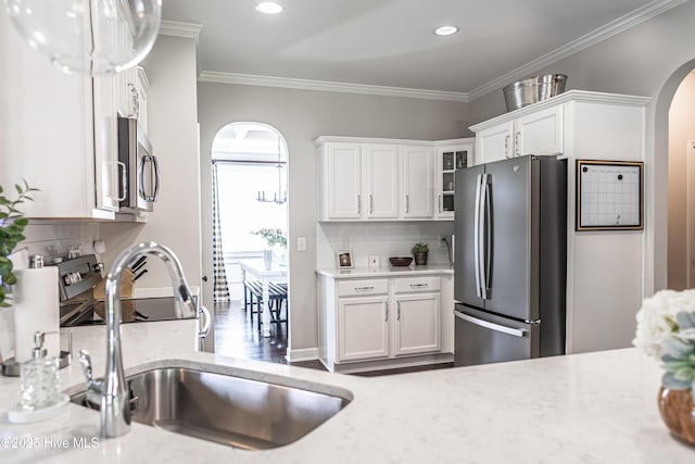 180 Cashew Loop, Cameron, NC 28326 - kitchen with decorative backsplash, arched walkways, white cabinets, a sink, and appliances with stainless steel finishes