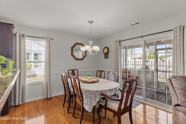 dining room with a chandelier, light wood finished floors, and baseboards