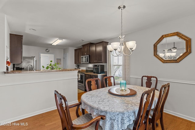 dining room featuring light wood-style floors, baseboards, and a chandelier