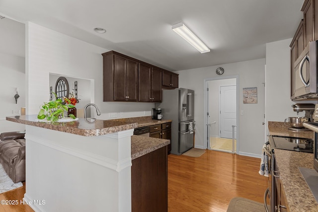 kitchen with stainless steel appliances, light wood-style floors, dark brown cabinetry, and a peninsula