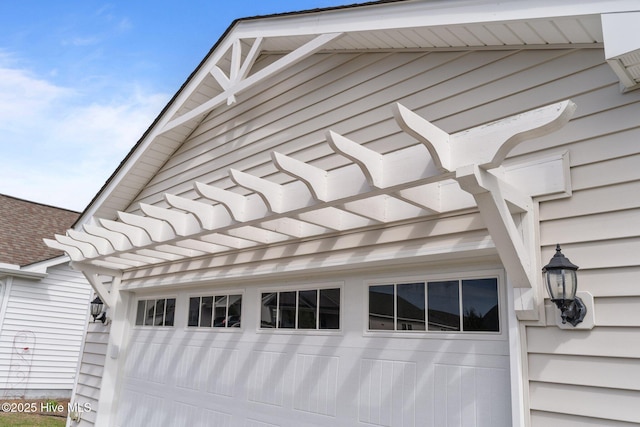 view of side of property featuring a garage and roof with shingles