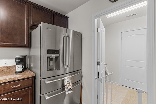 kitchen featuring stainless steel refrigerator with ice dispenser, dark brown cabinets, and baseboards
