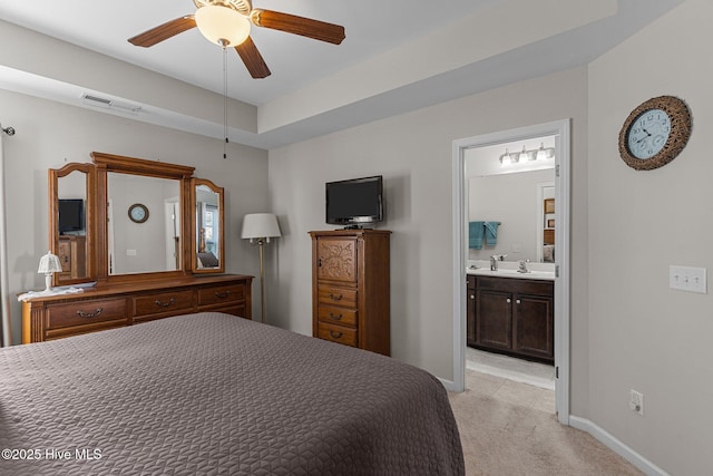 bedroom with light colored carpet, connected bathroom, baseboards, and a ceiling fan