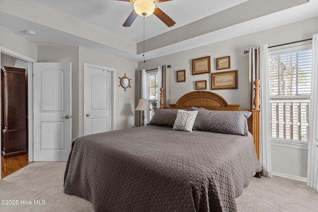 bedroom featuring light carpet, a ceiling fan, and baseboards