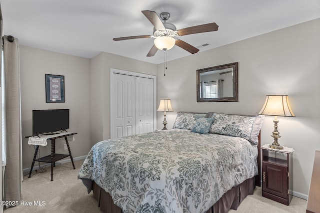 bedroom featuring light carpet, a closet, baseboards, and a ceiling fan