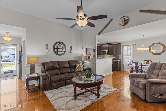 living area featuring ceiling fan, light wood-style floors, a chandelier, and baseboards