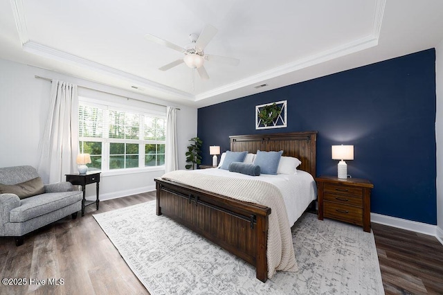 bedroom with baseboards, a raised ceiling, and wood finished floors