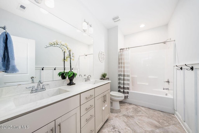 bathroom featuring toilet, double vanity, a sink, and visible vents