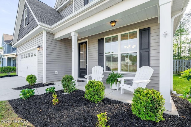 property entrance featuring driveway, a shingled roof, covered porch, and fence
