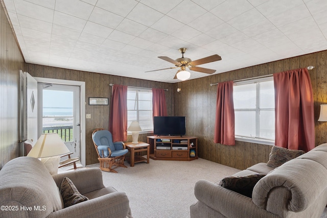 living area with wood walls, carpet, and ceiling fan