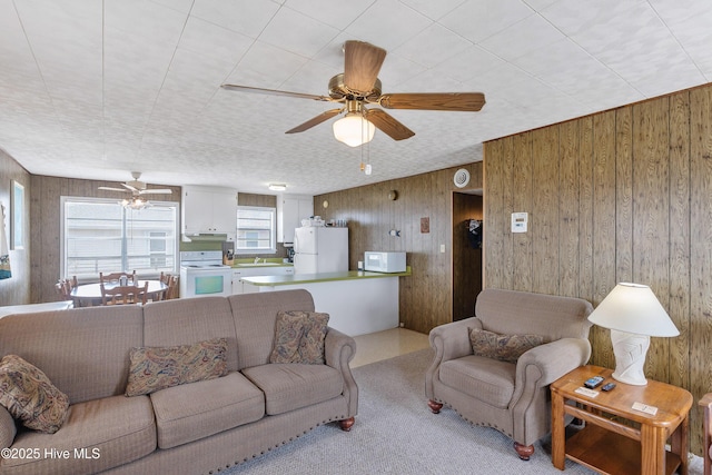 living area featuring a ceiling fan and wooden walls