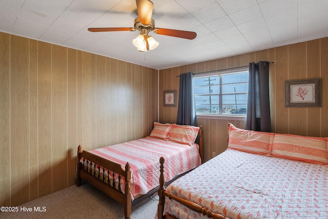 bedroom featuring wood walls, ceiling fan, and carpet floors