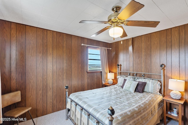 bedroom featuring wood walls, ceiling fan, and carpet floors