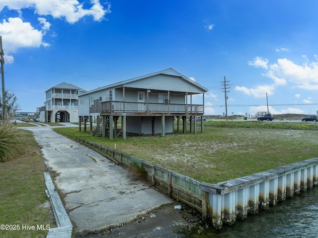 rear view of house featuring a deck, concrete driveway, and a yard