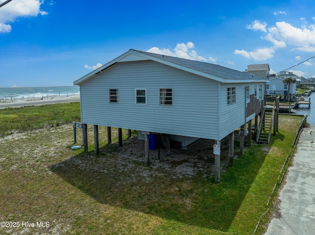 view of side of home with stairs, a water view, and a shingled roof
