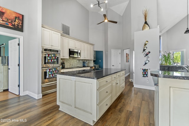 111 Waterway Ct, Aydlett, NC 27916 - kitchen with appliances with stainless steel finishes, high vaulted ceiling, baseboards, cream cabinetry, and a warming drawer