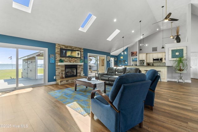 111 Waterway Ct, Aydlett, NC 27916 - living area with visible vents, dark wood-style flooring, a stone fireplace, high vaulted ceiling, and a skylight