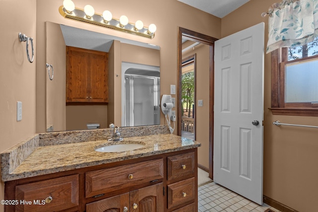 bathroom with baseboards, toilet, vanity, and a stall shower