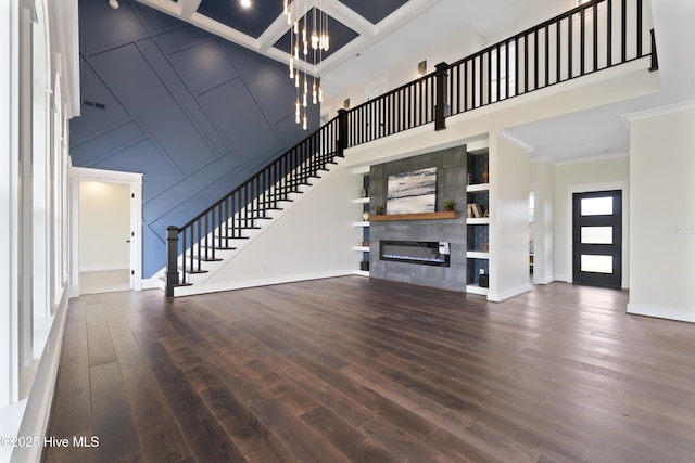 unfurnished living room with a towering ceiling, a chandelier, stairway, crown molding, and wood-type flooring