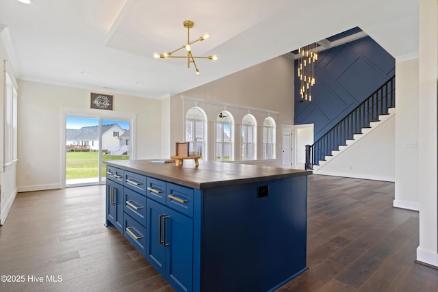 kitchen featuring a notable chandelier, a center island, wood counters, dark wood finished floors, and blue cabinetry