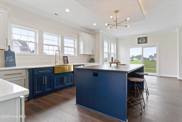 kitchen featuring blue cabinets, a sink, an inviting chandelier, crown molding, and a kitchen island