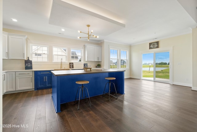 kitchen with dark wood-style floors, a sink, crown molding, a center island, and a chandelier