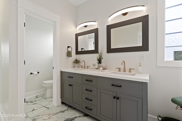 bathroom featuring marble finish floor, a sink, double vanity, and toilet