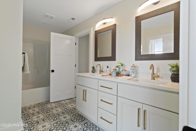 full bath featuring a bath, double vanity, visible vents, and a sink