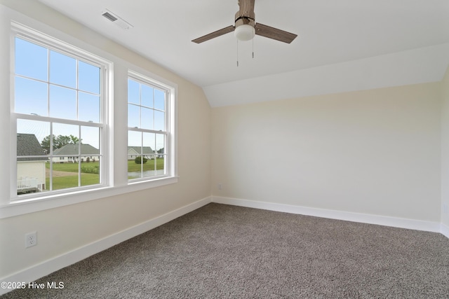 carpeted spare room featuring baseboards, vaulted ceiling, visible vents, and ceiling fan