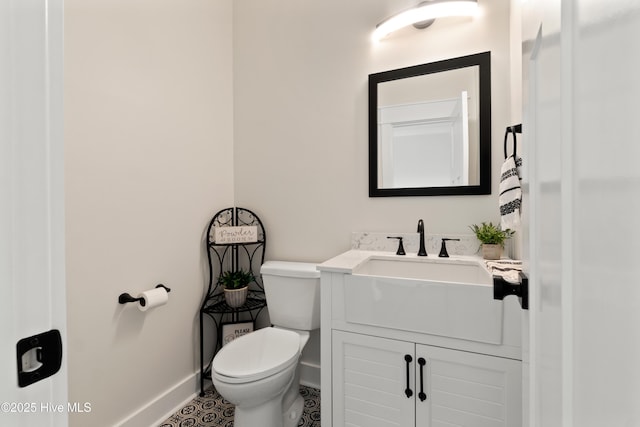 half bath featuring baseboards, vanity, and toilet