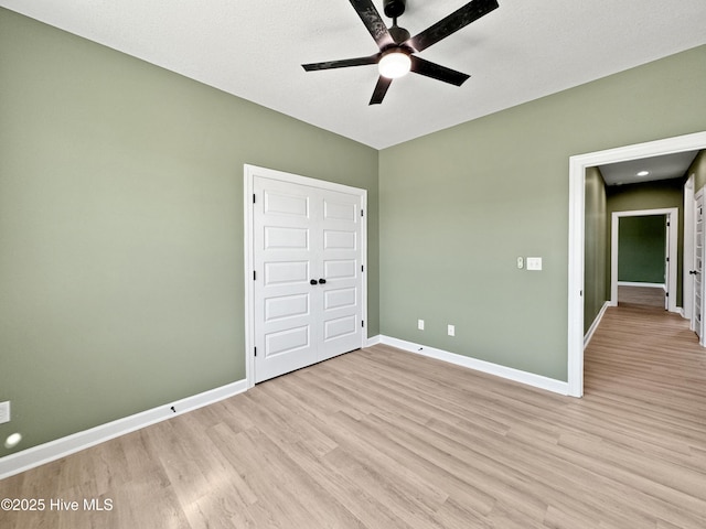 unfurnished bedroom featuring light wood-type flooring, baseboards, and ceiling fan