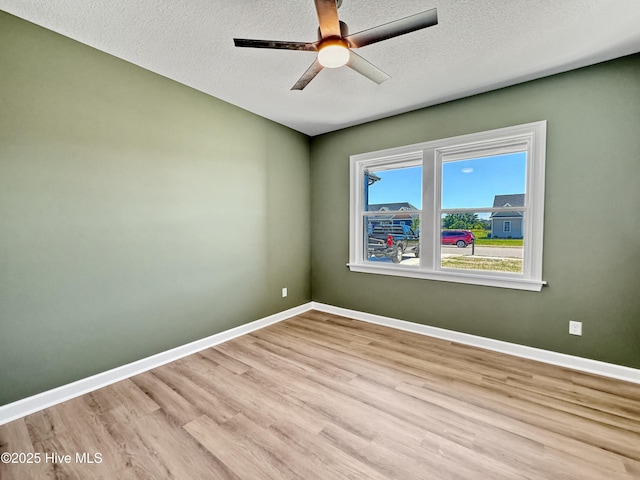spare room featuring baseboards, a ceiling fan, wood finished floors, and a textured ceiling