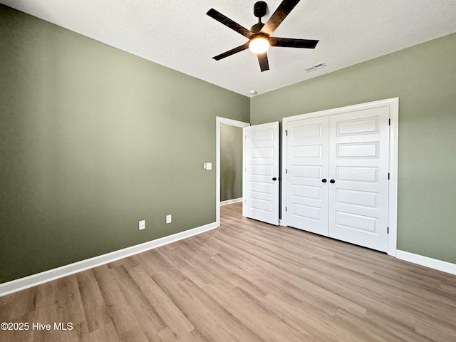 unfurnished bedroom with light wood finished floors, baseboards, visible vents, a closet, and ceiling fan
