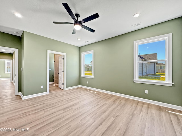 unfurnished bedroom featuring light wood finished floors, baseboards, and multiple windows