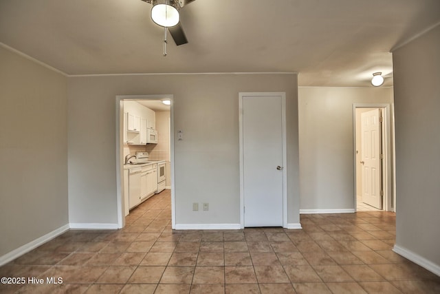 spare room featuring a sink, baseboards, a ceiling fan, crown molding, and light tile patterned floors