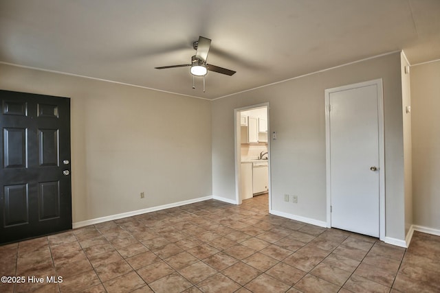 empty room with baseboards, a ceiling fan, and a sink