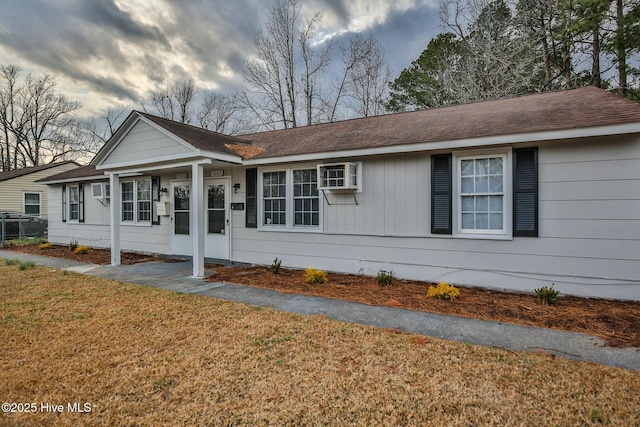 ranch-style house featuring a shingled roof and a front yard