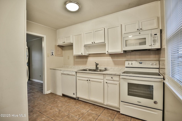 kitchen with a sink, white appliances, light tile patterned floors, light countertops, and baseboards