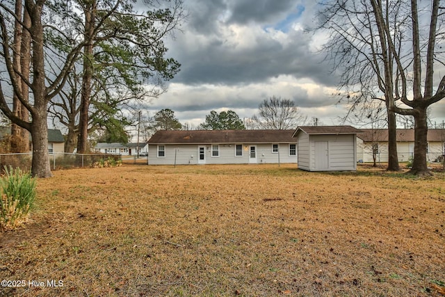back of property with a fenced backyard, an outbuilding, a yard, and a storage shed