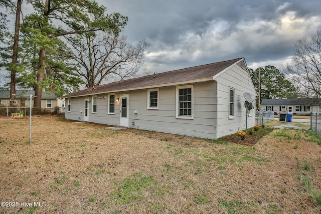 rear view of property featuring a fenced backyard and a lawn