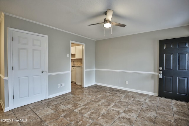 unfurnished bedroom featuring ceiling fan, baseboards, crown molding, and a sink