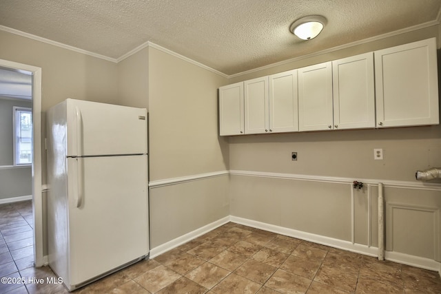 washroom with cabinet space, a textured ceiling, crown molding, and hookup for an electric dryer
