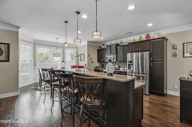 6509 Fawn Settle Dr, Wilmington, NC 28409 - kitchen with stainless steel appliances, backsplash, dark wood-type flooring, crown molding, and an island with sink